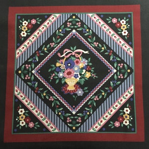 May include: A black and white fabric with a diamond pattern and a floral basket design in the center. The basket is filled with pink, purple, and yellow flowers. The fabric is surrounded by a red border.