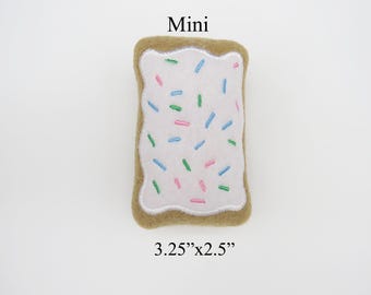May include: A mini felt  'Pop-Tart' style  plush toy with a white frosting and colorful sprinkles. The toy is 3.25 inches by 2.5 inches.