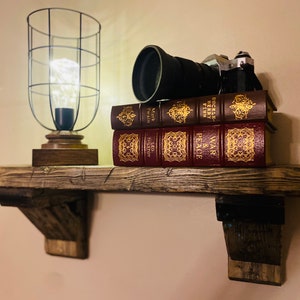 May include: A rustic wooden shelf with a caged light bulb, a vintage camera, and three books. The books are "War and Peace" by Leo Tolstoy, "The Red and the Black" by Stendhal, and "The Adventures of Huckleberry Finn" by Mark Twain.