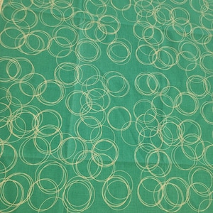 May include: Green fabric with a white circle pattern. The circles are overlapping and some are outlined.