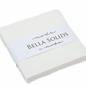 May include: A stack of white fabric squares, wrapped with a white band featuring the text "moda BELLA SOLIDS by moda". The edges of the fabric are neatly aligned, creating a clean, organized appearance. Ideal for quilting and fabric crafts.