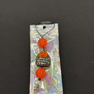 May include: A Halloween-themed retractable badge holder with orange pumpkin beads and a charm that reads "Fall is my 2nd favorite F-Word." The holder has a silver clip and is packaged in a holographic bag.