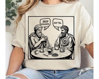 Peut inclure: T-shirt beige avec un motif noir et blanc de deux figures classiques autour d'une table avec des tasses à café. Des bulles de dialogue au-dessus d'eux indiquent "Deep Thoughts" et "Hot Tea."