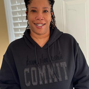 Könnte beinhalten: Schwarzer Kapuzenpullover mit dem Text "dream plan execute COMMIT" in silbernen Glitzerbuchstaben.