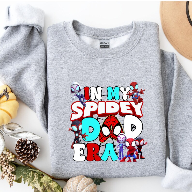 Puede incluir: Sudadera gris con un estampado gr&aacute;fico de personajes de Spider-Man y el texto "In My Spidey Dad Era".