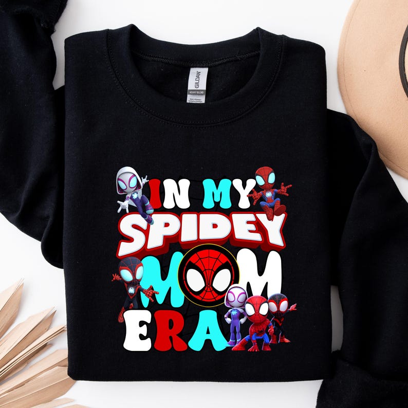 Puede incluir: Sudadera negra con un estampado gr&aacute;fico de personajes de Spider-Man y el texto "In My Spidey Mom Era".