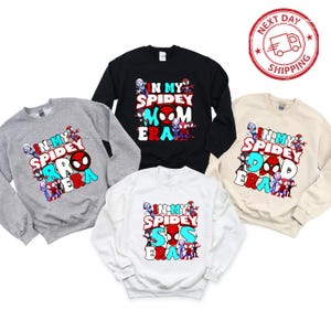 Puede incluir: Cuatro sudaderas con tem&aacute;tica de Spider-Man. Las sudaderas son de color negro, gris, blanco y beige. El texto en las sudaderas dice "In My Spidey [Role] Era" con un Spider-Man de dibujos animados y otros personajes.