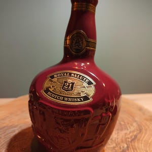 May include: A red ceramic bottle of Royal Salute 21 Years Old Blended Scotch Whisky. The bottle has a gold label with the Royal Salute logo and the words "21 Years Old Blended Scotch Whisky".