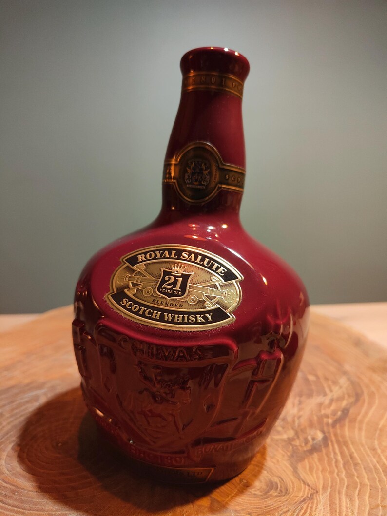 May include: A red ceramic bottle of Royal Salute 21 Years Old Blended Scotch Whisky. The bottle has a gold label with the Royal Salute logo and the words "21 Years Old Blended Scotch Whisky".