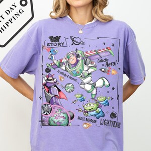 A woman wearing a purple t-shirt with a colorful graphic design featuring characters from the Toy Story movie, including Buzz Lightyear and a space ranger.