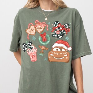 A person wearing a green t-shirt with various Christmas-themed illustrations, including a Santa hat, gingerbread man, and other festive decorations.