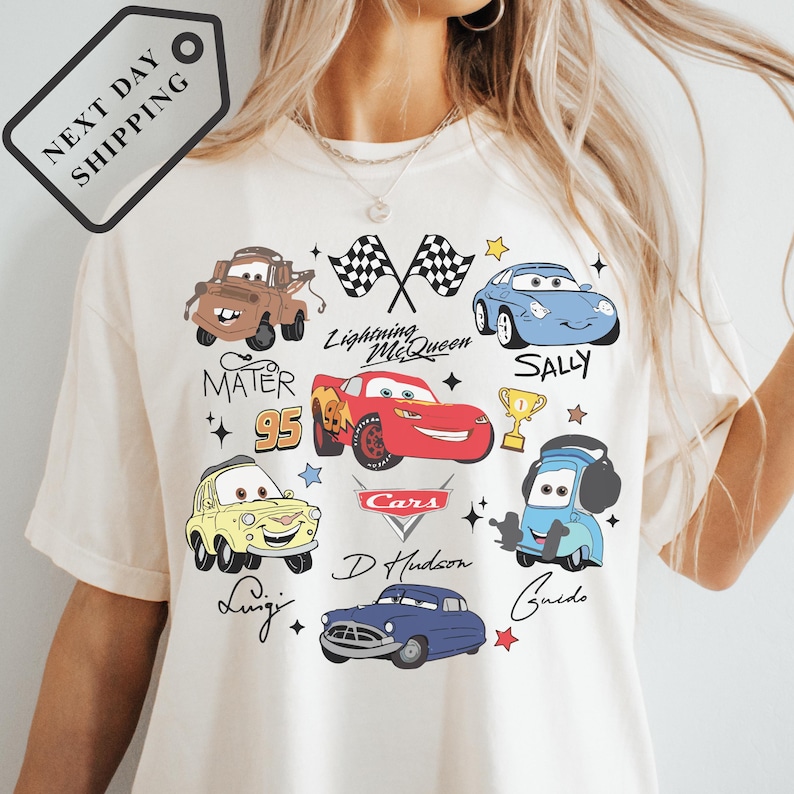 A white t-shirt with various cartoon car characters and logos printed on it.