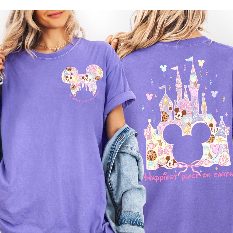 two women wearing purple t-shirts with Disney-themed designs. The t-shirts have a castle and Mickey Mouse motif, and the phrase "Happiest place on earth" is printed on the back.