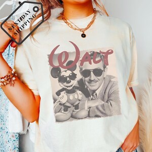 A person wearing a white t-shirt with a graphic of Walt Disney and Mickey Mouse.