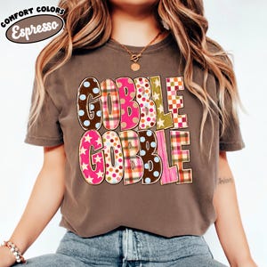 A woman wearing a brown t-shirt with the text "GOBBLE GOBBLE" printed on it.