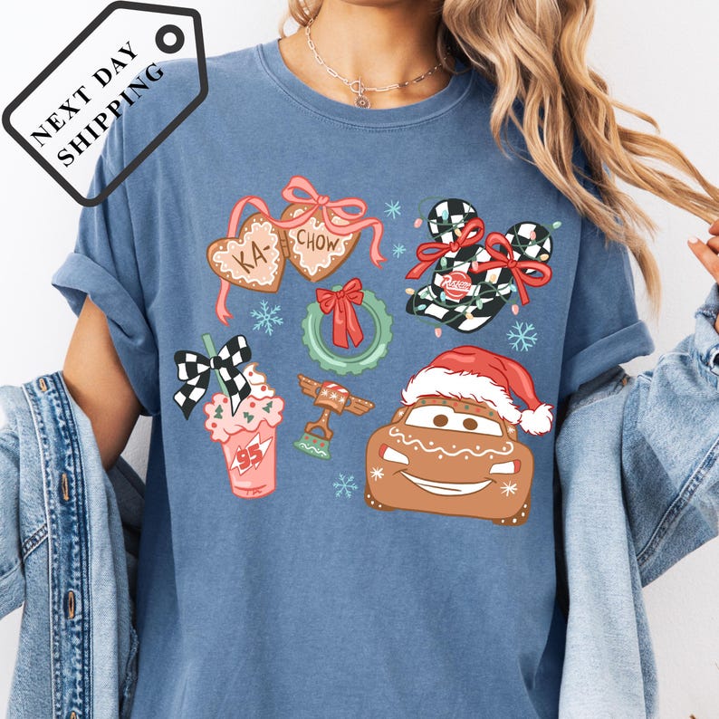 A blue t-shirt with various Christmas-themed illustrations, including a Santa hat, gingerbread man, and other festive decorations.