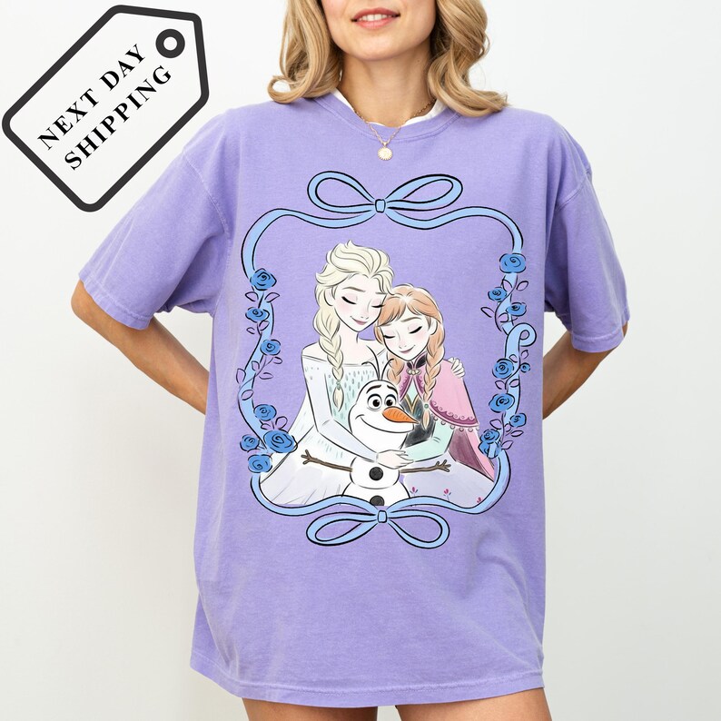 A woman wearing a purple t-shirt with a graphic design featuring characters from the Disney movie Frozen.