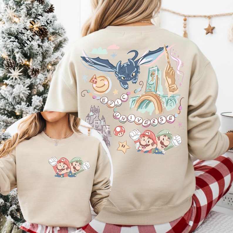 a woman wearing a beige sweatshirt with a colorful and whimsical design featuring Mario and other characters from the Super Mario video game franchise.