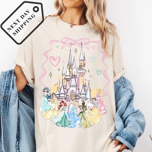 A woman wearing a white t-shirt with a Disney princess castle graphic printed on it.