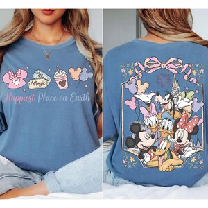 The image is a collage of two photos featuring a woman wearing a blue t-shirt with a Disney-themed design. The design includes various Disney characters such as Mickey Mouse, Minnie Mouse, Donald Duck, and Goofy. The woman is posing with the t-shirt, and the back view of the shirt shows the Disney characters and the text "Happiest Place on Earth".