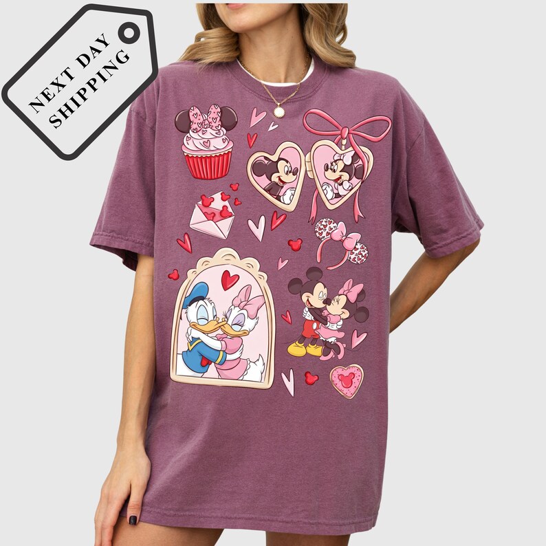 A woman wearing a purple t-shirt with a graphic design featuring Disney characters such as Minnie Mouse, Donald Duck, and Mickey Mouse, along with various heart-shaped and heart-studded elements.