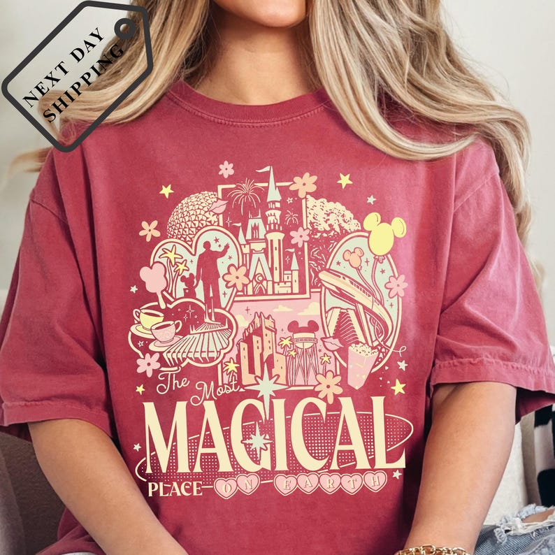 A person wearing a red t-shirt with a graphic design featuring various Disney-themed elements, including Mickey Mouse, a castle, and other iconic imagery.