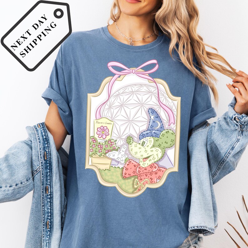 A woman wearing a blue t-shirt with a graphic design of Mickey Mouse and various other cartoon-like elements.