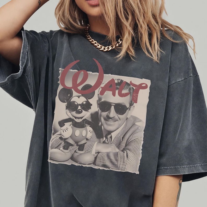 A woman wearing a gray t-shirt with a graphic design featuring a man and a child, along with the text "WALT".