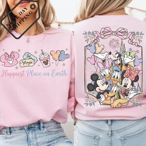 a woman wearing a pink sweater with a Disney-themed design on the back.