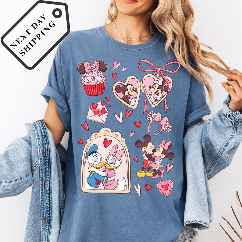 A woman wearing a blue t-shirt with various Disney characters and illustrations, including Minnie Mouse, Donald Duck, and Mickey Mouse.
