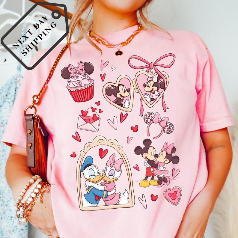 A woman wearing a pink t-shirt with various Disney characters and heart-shaped designs printed on it.