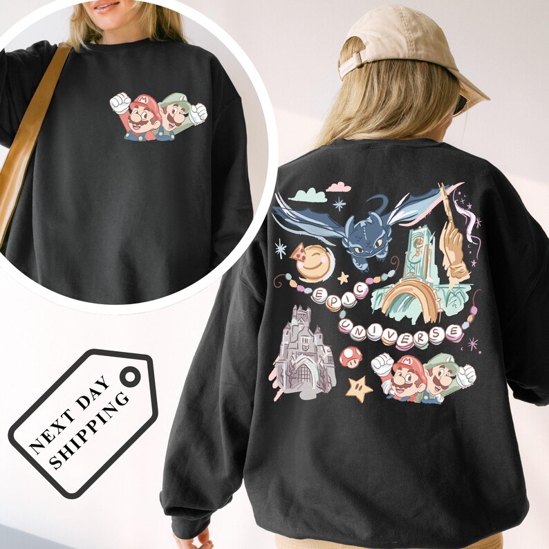 A person wearing a black sweatshirt with a colorful graphic design featuring Mario, a cat, and various other characters and elements.