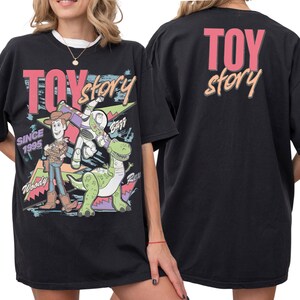 A black t-shirt with a colorful graphic design featuring characters from the Toy Story movie, including Woody and Buzz Lightyear.