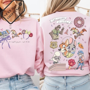 a woman wearing a pink sweatshirt with various cartoon characters and designs on the back.