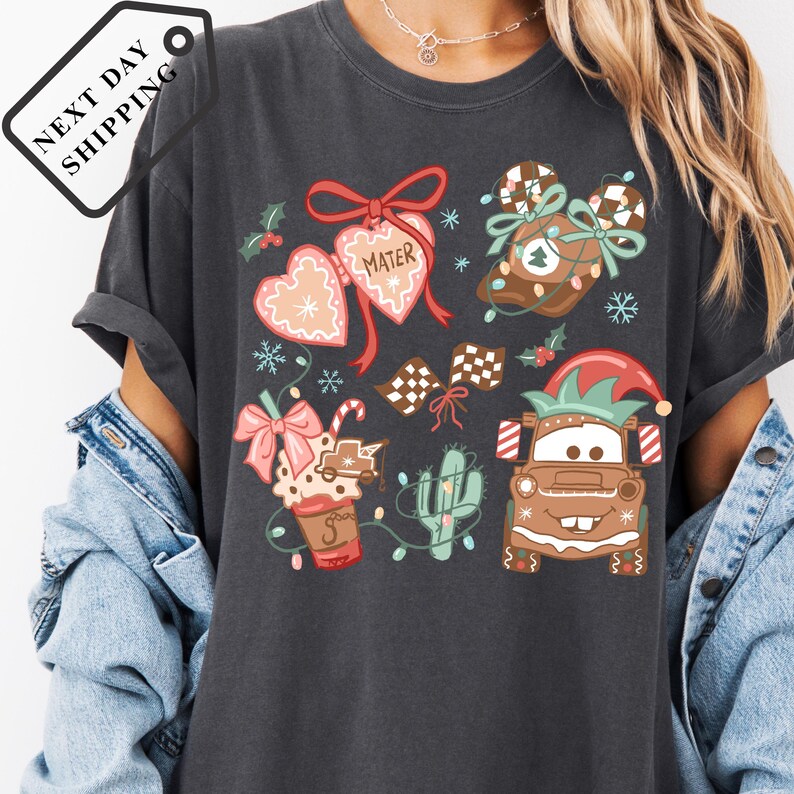 A person wearing a gray t-shirt with a Christmas-themed design featuring various holiday-related items such as a gingerbread man, a snowman, and other festive decorations.