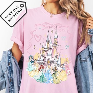 A woman wearing a pink t-shirt with a Disney princess castle design.