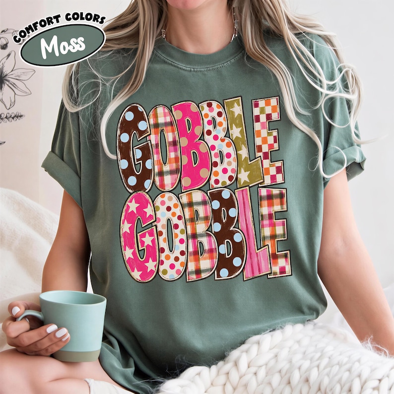 A person wearing a green t-shirt with the word "GOBBLE GOBBLE" printed on it, sitting on a bed with a cup of coffee.