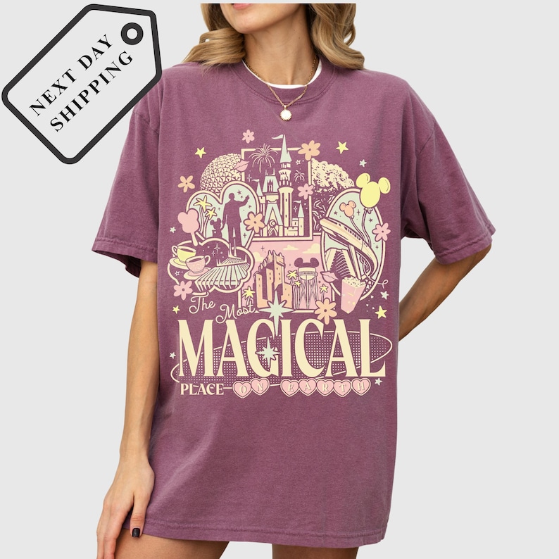 A woman wearing a purple t-shirt with a graphic design featuring various Disney-themed elements, including Mickey Mouse, the Eiffel Tower, and other iconic landmarks.