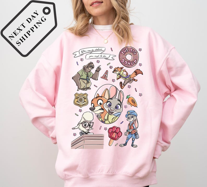 A woman wearing a pink sweatshirt with a cartoon character design featuring various cartoon animals and objects.