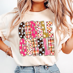 A woman wearing a white t-shirt with the text "GOBBLE GOBBLE" printed on it.