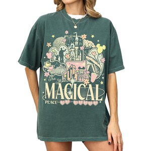A green t-shirt with a graphic design featuring various Disney-themed elements, including a castle, Mickey Mouse, and other iconic imagery.