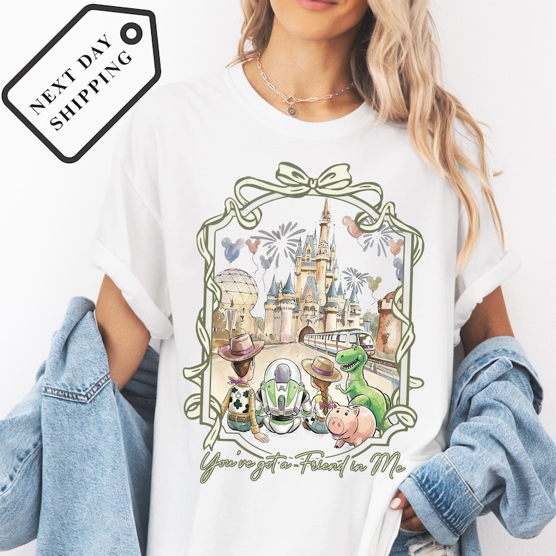 A woman wearing a white t-shirt with a graphic design featuring a castle, a dinosaur, and various other characters.