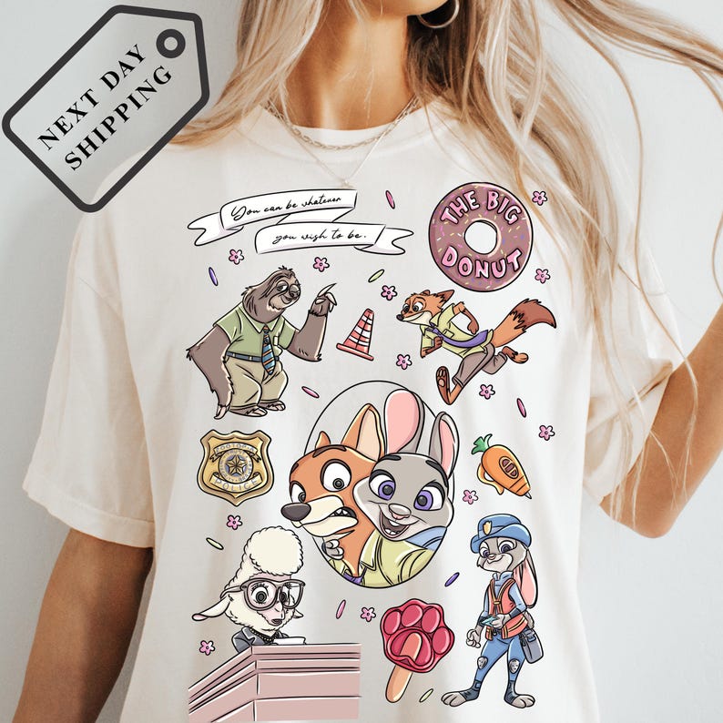A white t-shirt with a colorful graphic design featuring various cartoon characters, including a police officer, a fox, and other animals.
