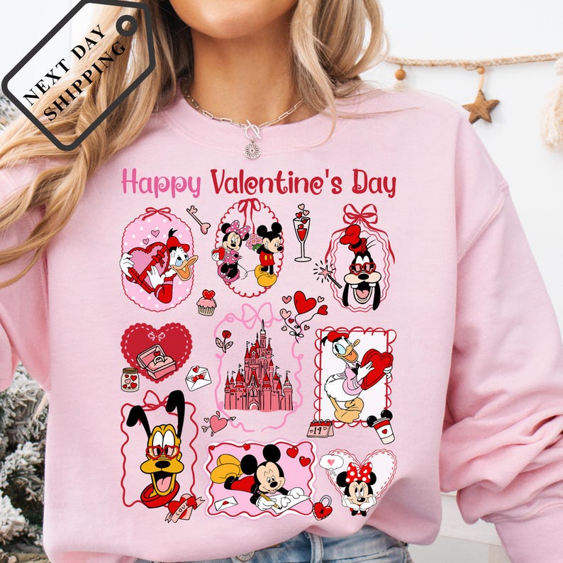 A woman wearing a pink sweatshirt with a collage of Disney characters and Valentine's Day-themed illustrations.