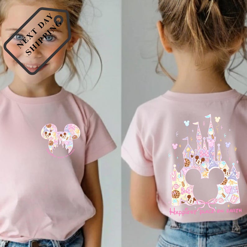 A young girl wearing a pink t-shirt with a Mickey Mouse design and a castle graphic on the back.