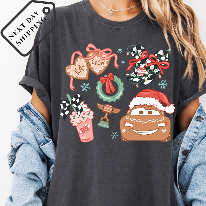 A person wearing a gray t-shirt with various Christmas-themed graphics and icons, including a Santa hat, gingerbread houses, and other festive elements.