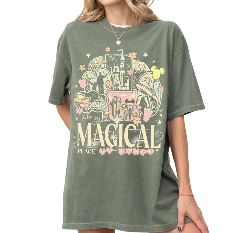 A woman wearing a green t-shirt with a graphic design featuring various Disney-themed elements such as Mickey Mouse, castles, and other iconic imagery.