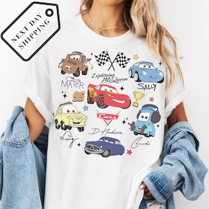A person wearing a white t-shirt with various cartoon car characters and designs printed on it.