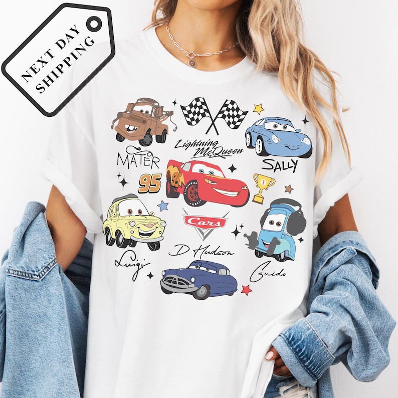 A person wearing a white t-shirt with various cartoon car characters and designs printed on it.