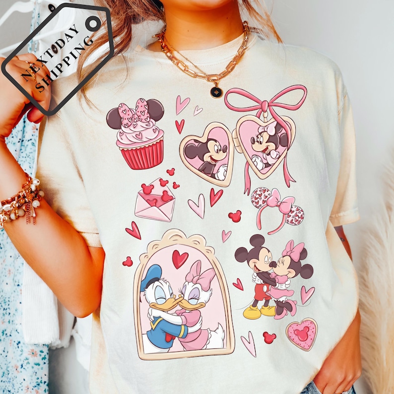 A person wearing a white t-shirt with various Disney characters and heart-shaped designs printed on it.